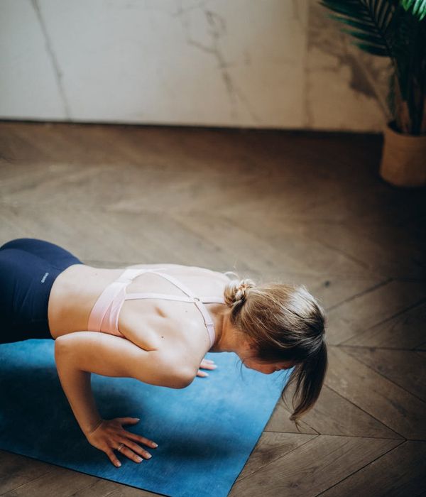 Woman in a calm yoga pose in a dark room.